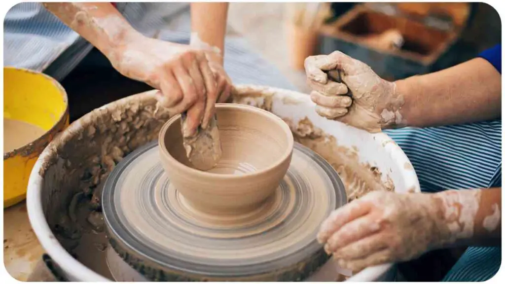 two individuals are making a pot on a potter's wheel