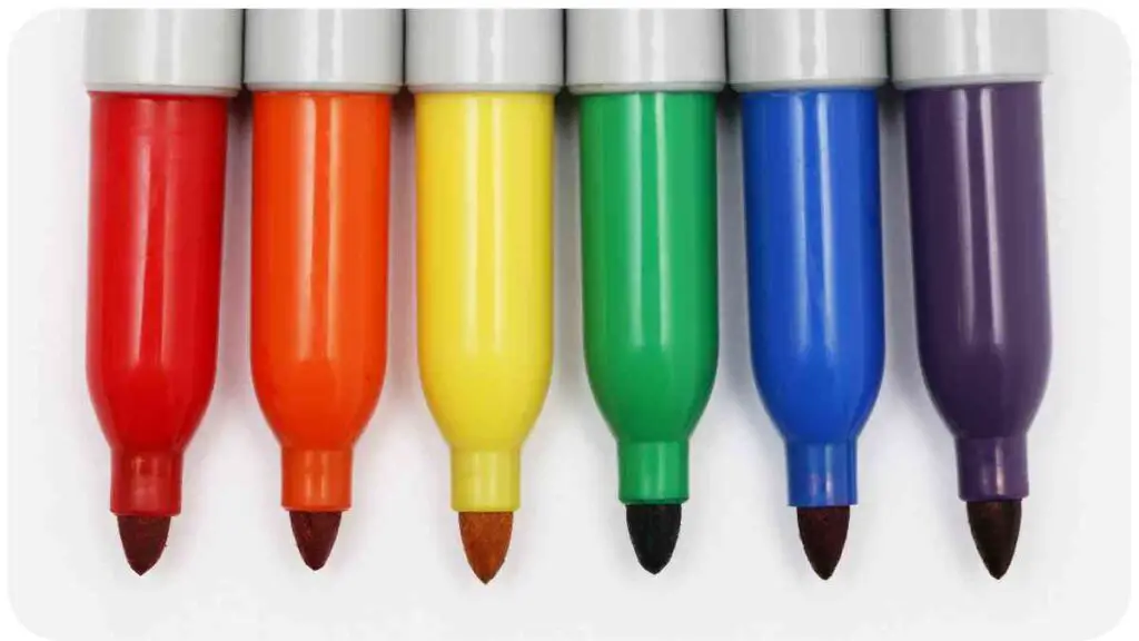 five different colored markers are lined up on a white surface